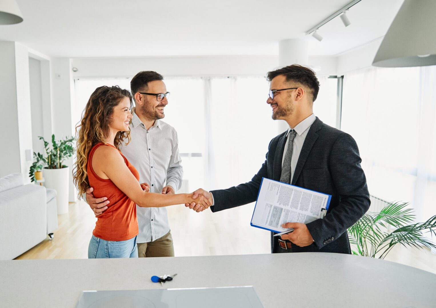 couple man deal woman contract business agent agreement estate investment consultant meeting document keys Couple shaking hands with real estate agent.
