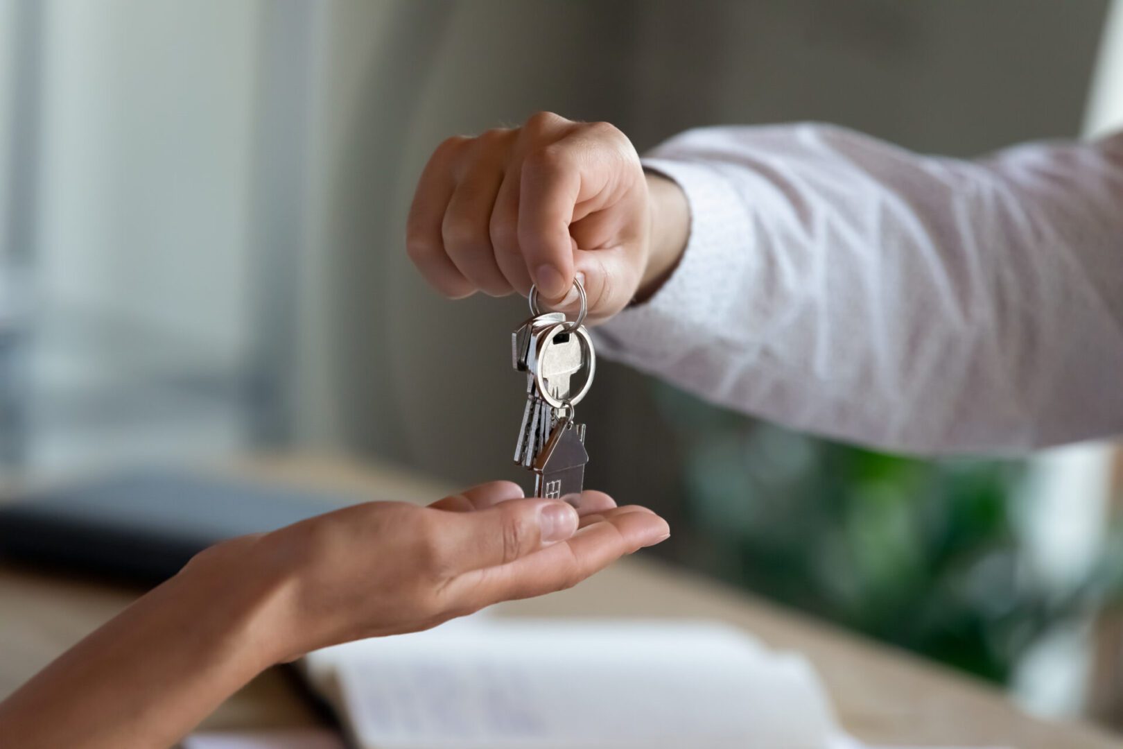 Close up professional Real estate agent giving keys to client. Hand giving house keys to another hand.