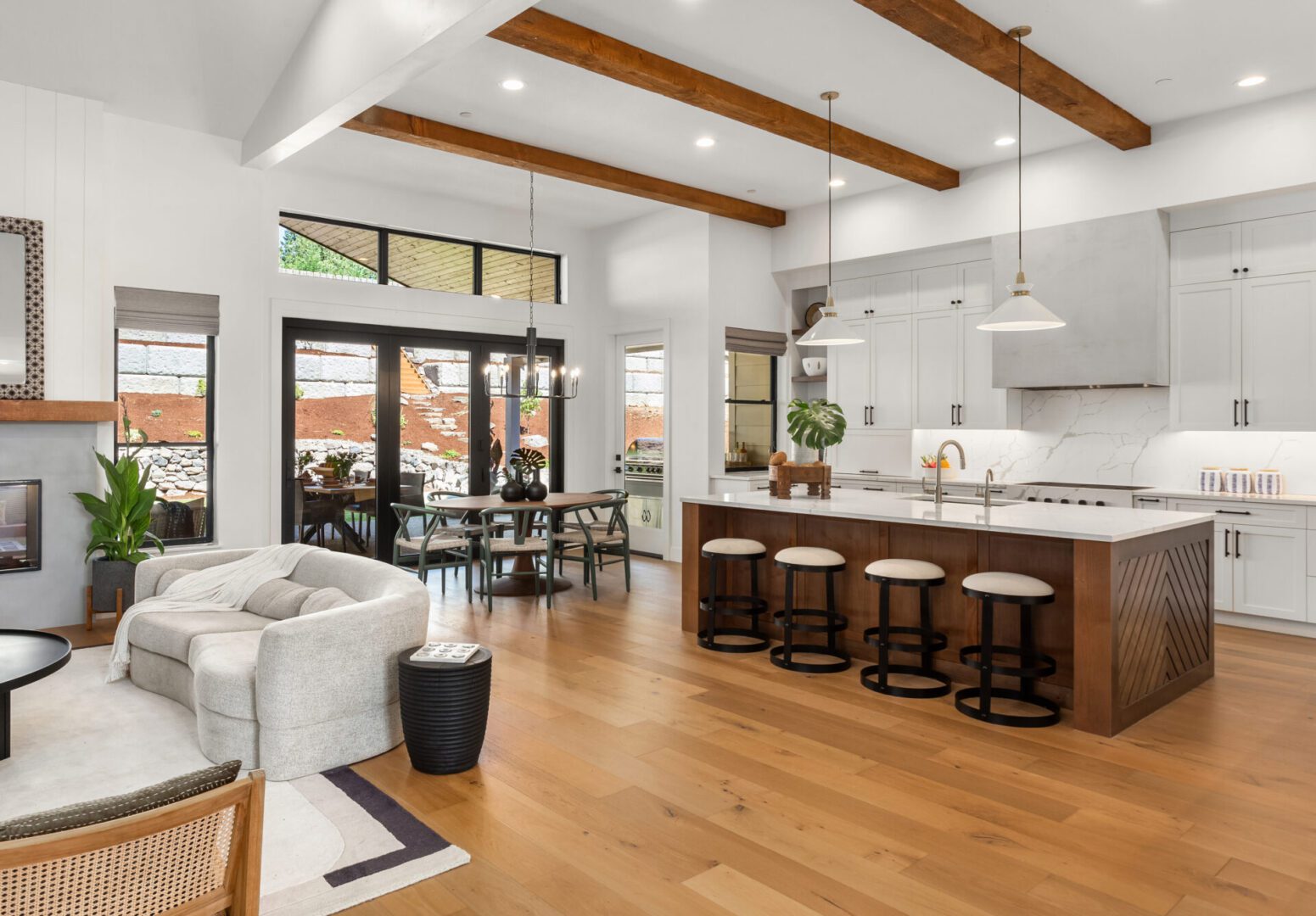 Beautiful living room and kitchen in new luxury home with white cabinets, wood beams, pendant lights and hardwood floors Modern open-plan kitchen and living area.
