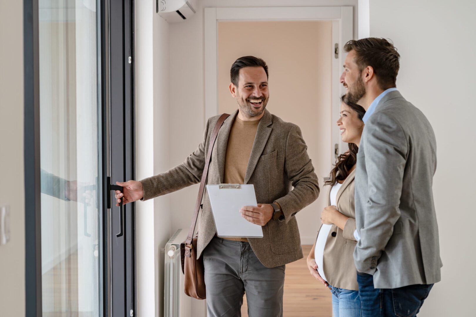 Young married couple talking with a real-estate agent visiting apartment for sale or for rent Real estate agent showing house to couple.